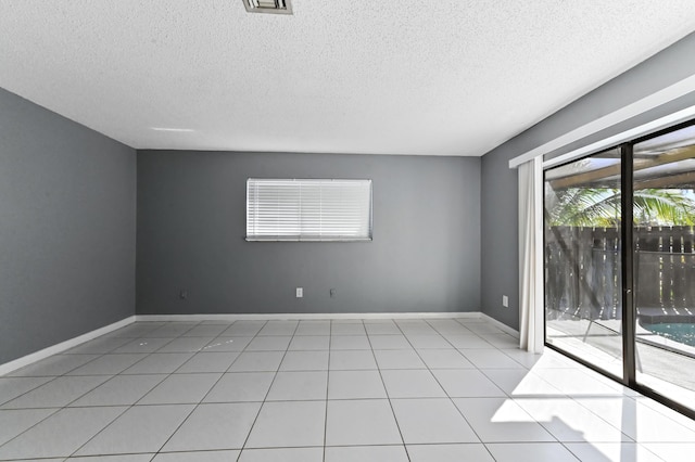 empty room with light tile patterned floors, baseboards, and a textured ceiling