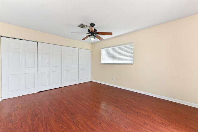 unfurnished bedroom with wood finished floors, visible vents, a closet, and baseboards