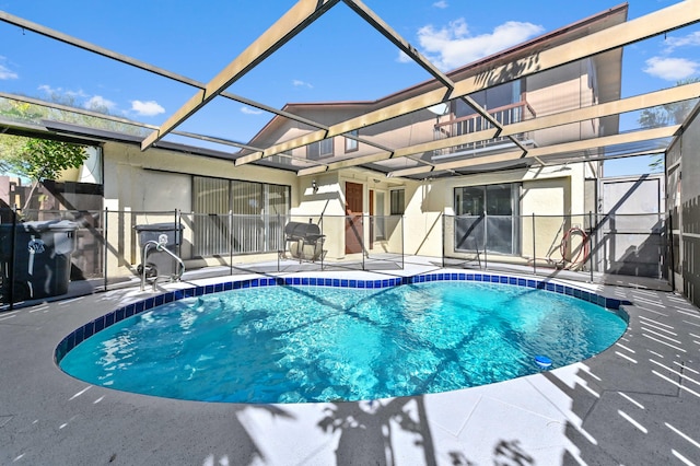 pool featuring glass enclosure, a patio, and area for grilling