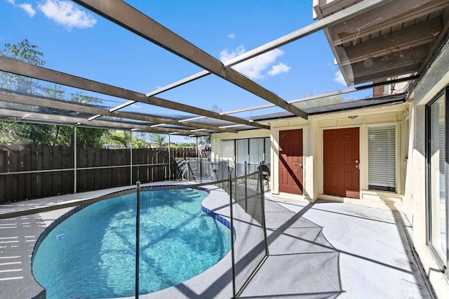 view of pool featuring glass enclosure, a patio, a fenced in pool, and fence