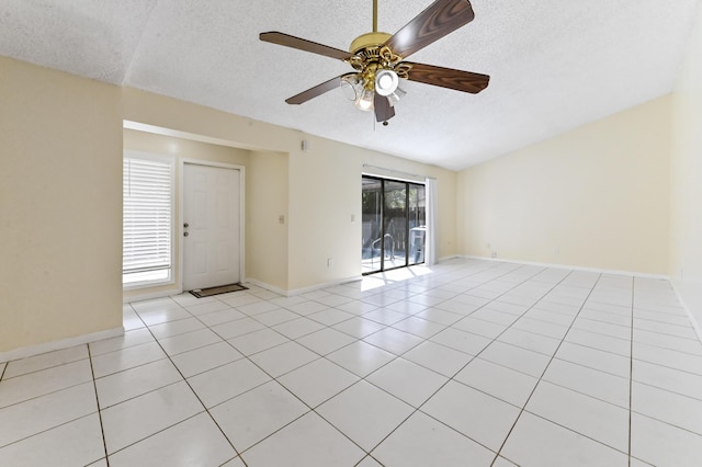 unfurnished room with ceiling fan, light tile patterned floors, baseboards, and a textured ceiling