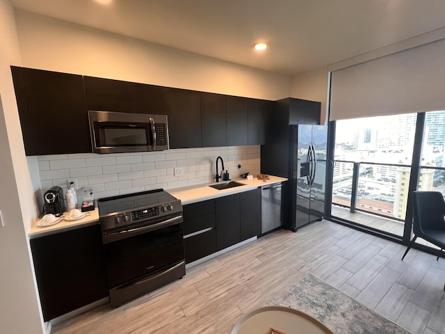 kitchen with light wood finished floors, light countertops, decorative backsplash, appliances with stainless steel finishes, and a sink