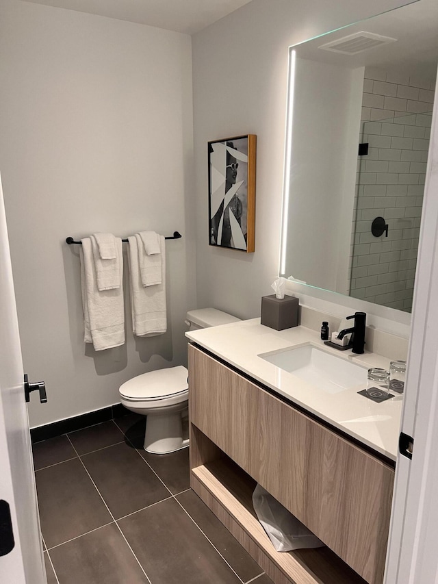 bathroom with baseboards, tiled shower, toilet, tile patterned floors, and vanity