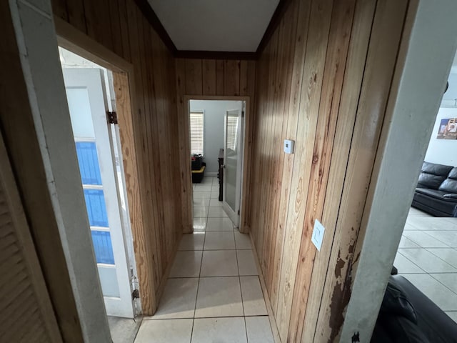 corridor with light tile patterned flooring and wooden walls