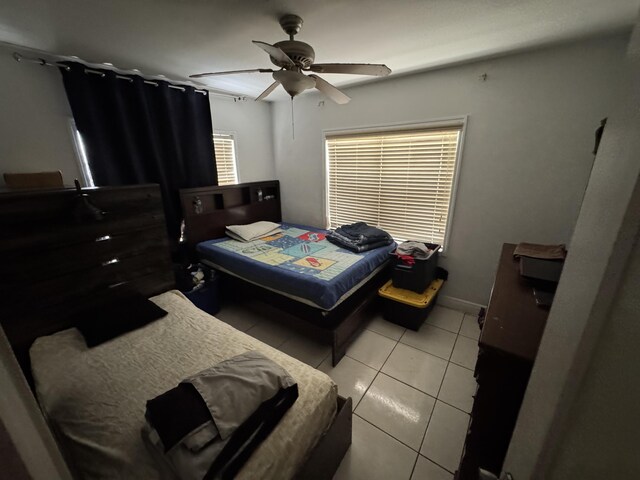 bedroom with ceiling fan, baseboards, and light tile patterned flooring