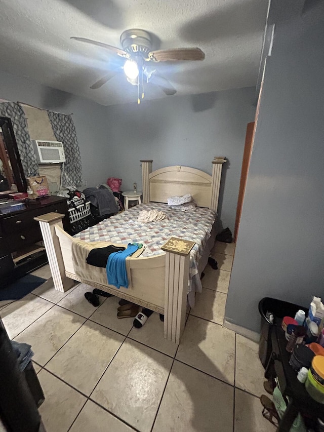 bedroom with a wall unit AC, light tile patterned floors, ceiling fan, and a textured ceiling