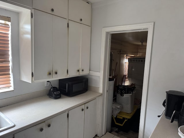 interior space with black microwave, light countertops, a sink, and white cabinets