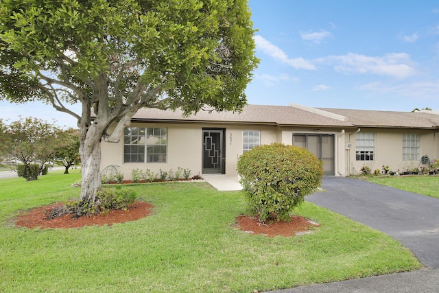 ranch-style house with a garage, aphalt driveway, a front yard, and stucco siding