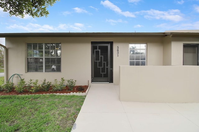 view of exterior entry featuring fence and stucco siding