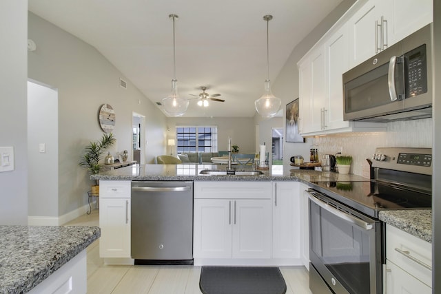 kitchen featuring pendant lighting, stainless steel appliances, white cabinets, a sink, and a peninsula