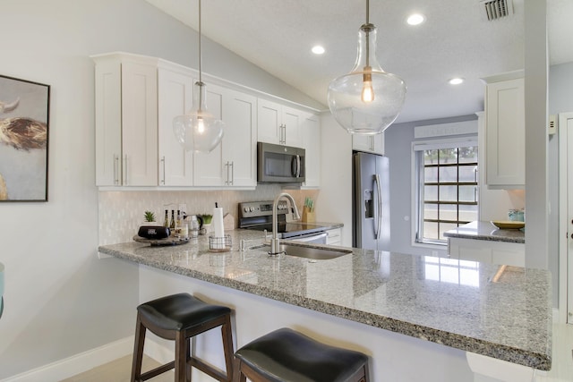 kitchen with lofted ceiling, visible vents, backsplash, appliances with stainless steel finishes, and a peninsula