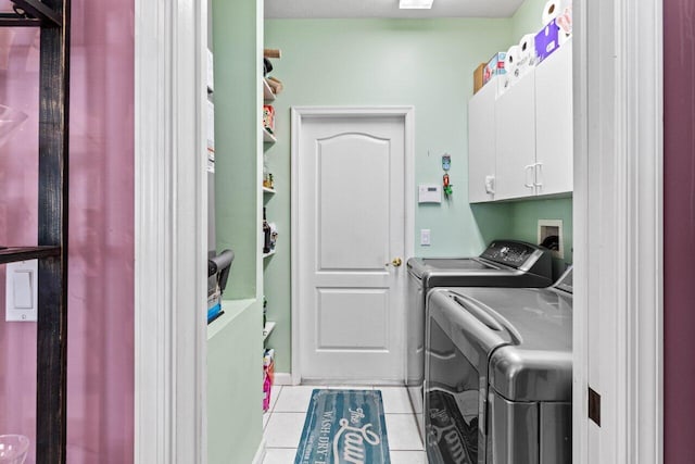 laundry room featuring washer and dryer, light tile patterned floors, and cabinet space