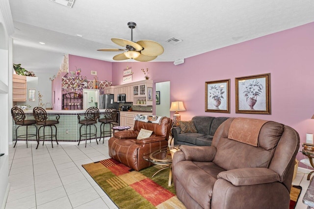 living room featuring light tile patterned flooring, a ceiling fan, visible vents, and a textured ceiling
