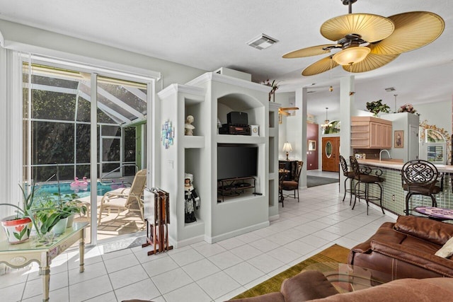 living area with visible vents, ceiling fan, a sunroom, light tile patterned flooring, and a textured ceiling