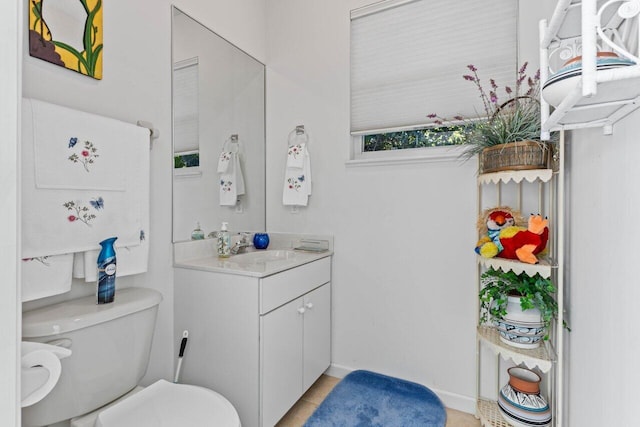 bathroom with baseboards, toilet, and vanity