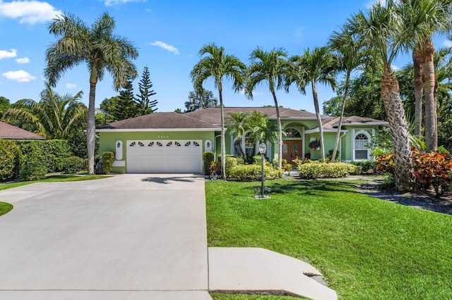 ranch-style home with stucco siding, an attached garage, driveway, and a front yard