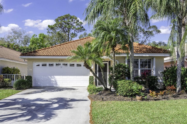 view of front of home with a garage, concrete driveway, a tile roof, and stucco siding