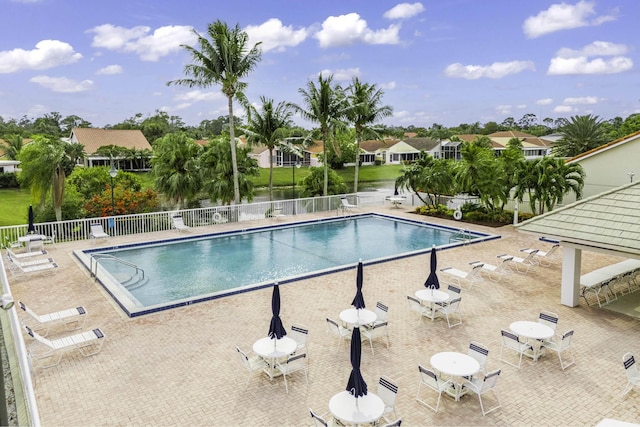 pool with a patio area, fence, and a residential view