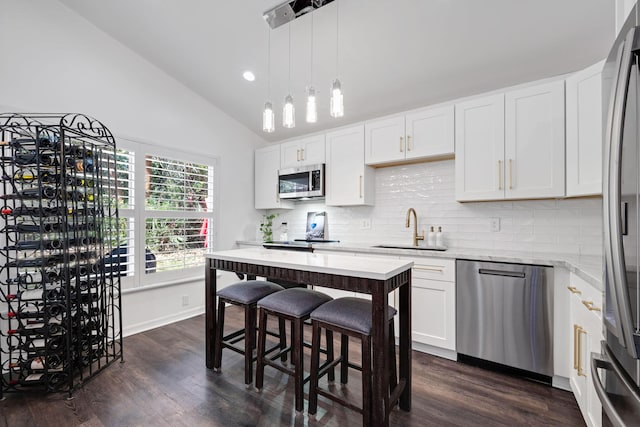 kitchen with decorative backsplash, lofted ceiling, dark wood-type flooring, stainless steel appliances, and a sink