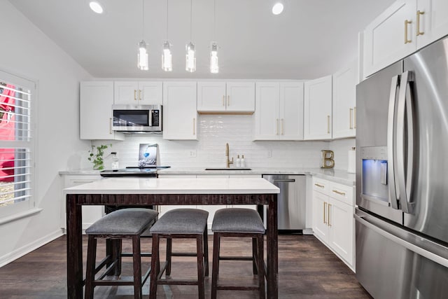 kitchen with stainless steel appliances, white cabinets, a sink, and backsplash