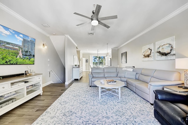 living room featuring baseboards, visible vents, dark wood finished floors, and ornamental molding