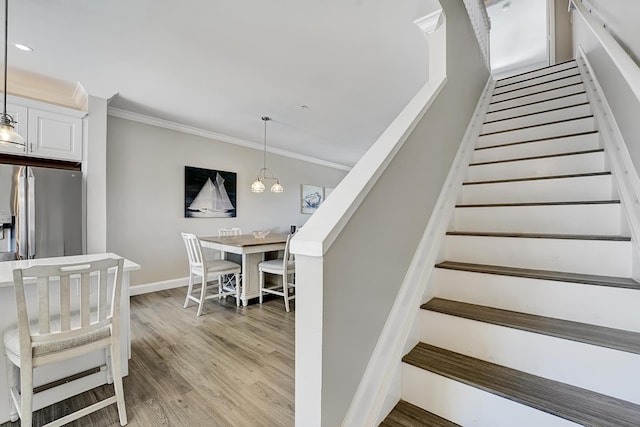 stairway with ornamental molding, recessed lighting, wood finished floors, and baseboards