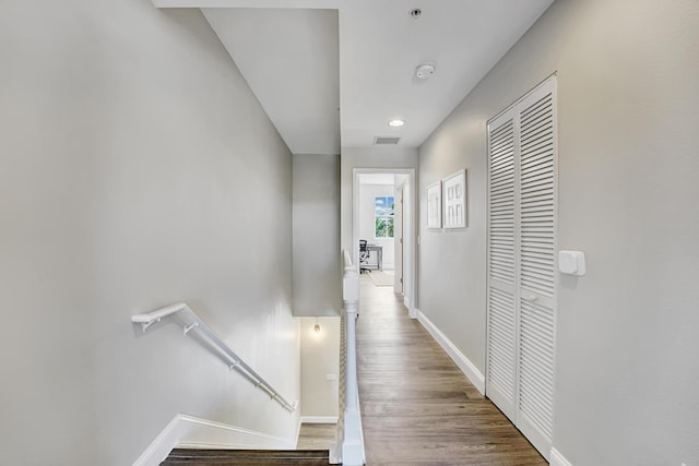 hall featuring wood finished floors, visible vents, and baseboards