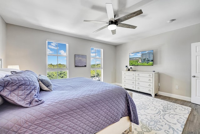 bedroom with ceiling fan, baseboards, and wood finished floors