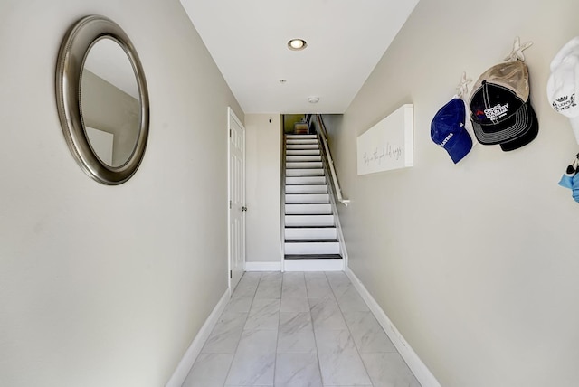 hallway featuring marble finish floor, stairs, and baseboards