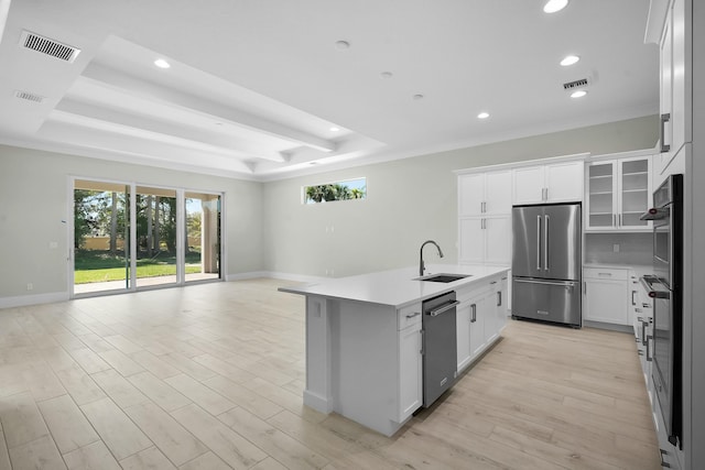 kitchen featuring appliances with stainless steel finishes, a tray ceiling, open floor plan, and a sink