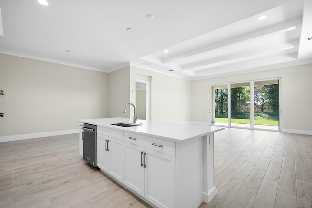 kitchen with a tray ceiling, light wood finished floors, open floor plan, a sink, and baseboards