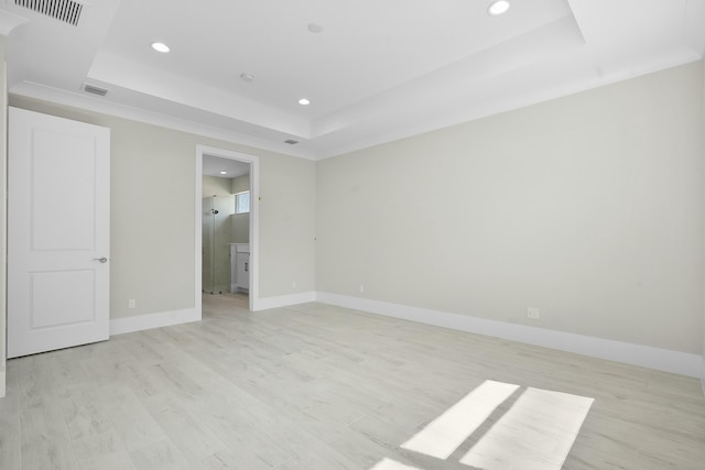 unfurnished bedroom with a raised ceiling, visible vents, light wood-style flooring, and baseboards