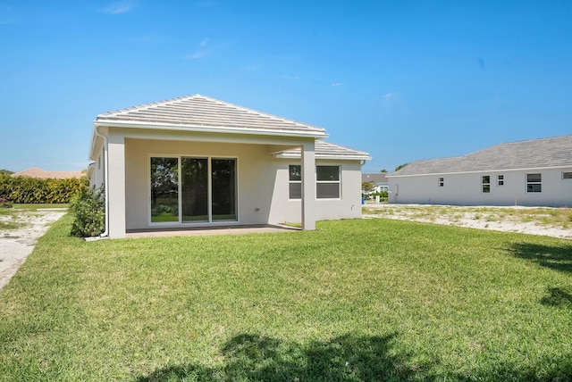 back of house with a lawn and stucco siding