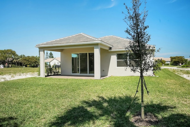 back of property with a yard, a patio, a tile roof, and stucco siding