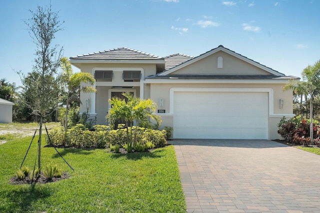 view of front facade with a front yard, decorative driveway, an attached garage, and stucco siding