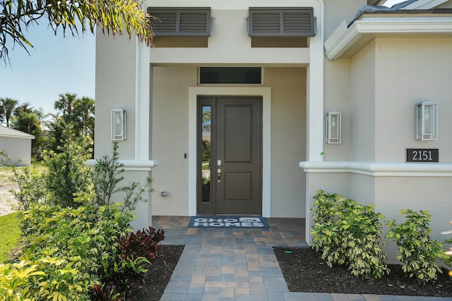 doorway to property featuring visible vents and stucco siding