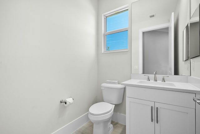 bathroom with visible vents, toilet, vanity, wood finished floors, and baseboards