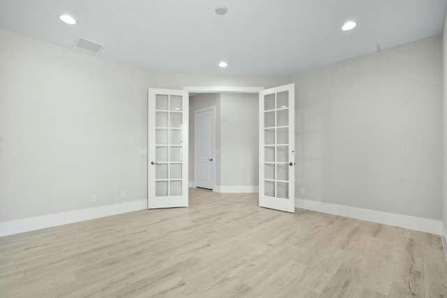 unfurnished room with visible vents, wood finished floors, and french doors