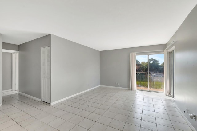 spare room with light tile patterned floors and baseboards