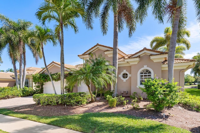 mediterranean / spanish home with driveway, a tile roof, a garage, and stucco siding