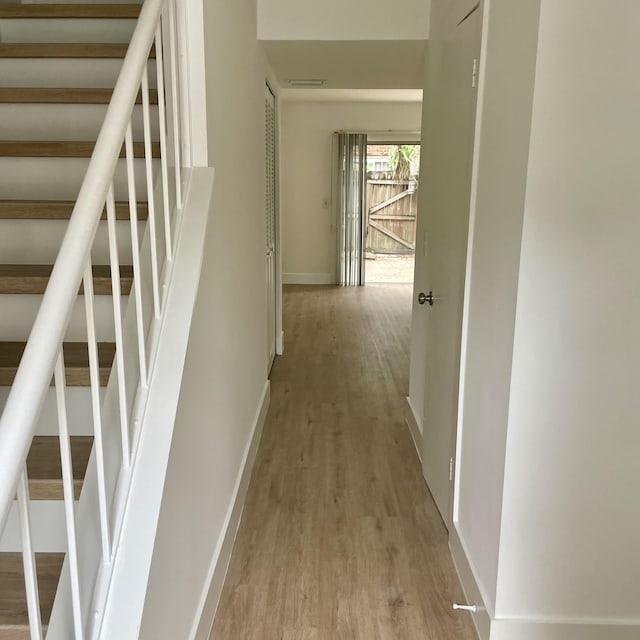 hall with stairway, baseboards, and wood finished floors