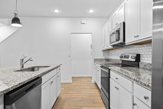 2349 SE Union Park Dr, Port Saint Lucie, FL 34952 - kitchen with light stone counters, backsplash, appliances with stainless steel finishes, light wood finished floors, and a sink