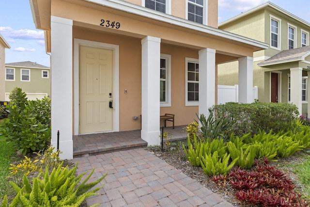 property entrance with a porch and stucco siding