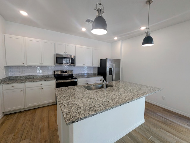 kitchen with wood finished floors, a sink, visible vents, appliances with stainless steel finishes, and backsplash