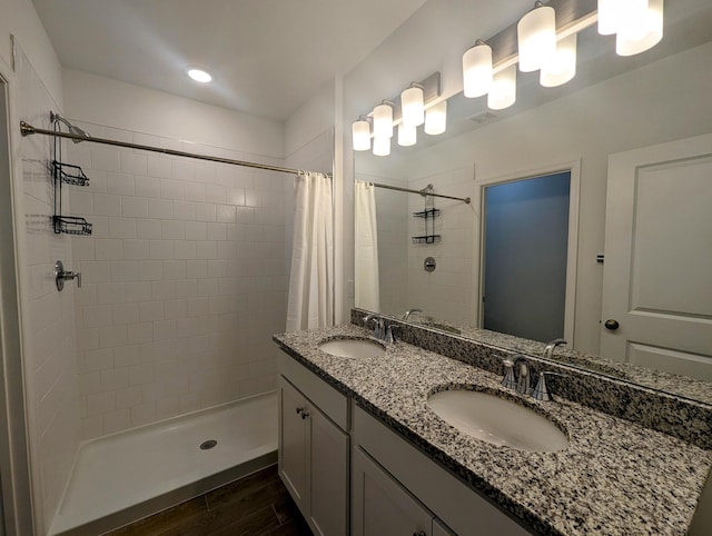 full bath with double vanity, wood finished floors, a sink, and a shower stall