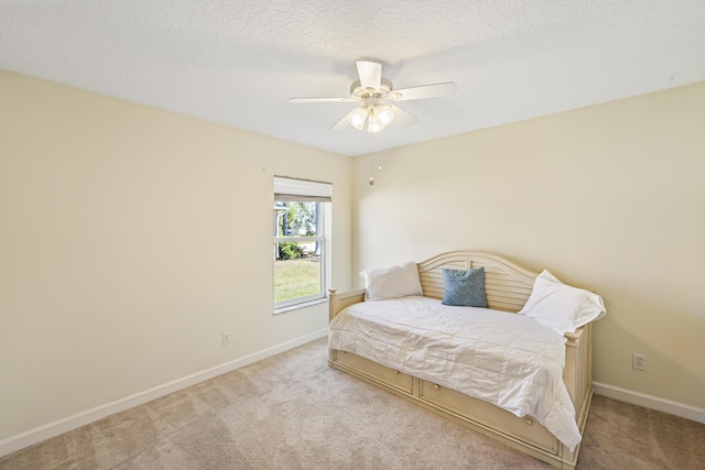 carpeted bedroom with a ceiling fan, baseboards, and a textured ceiling