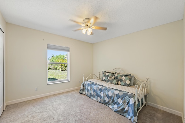 bedroom featuring ceiling fan, a textured ceiling, baseboards, and carpet