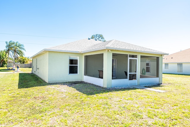 back of house featuring a lawn, roof with shingles, and a sunroom