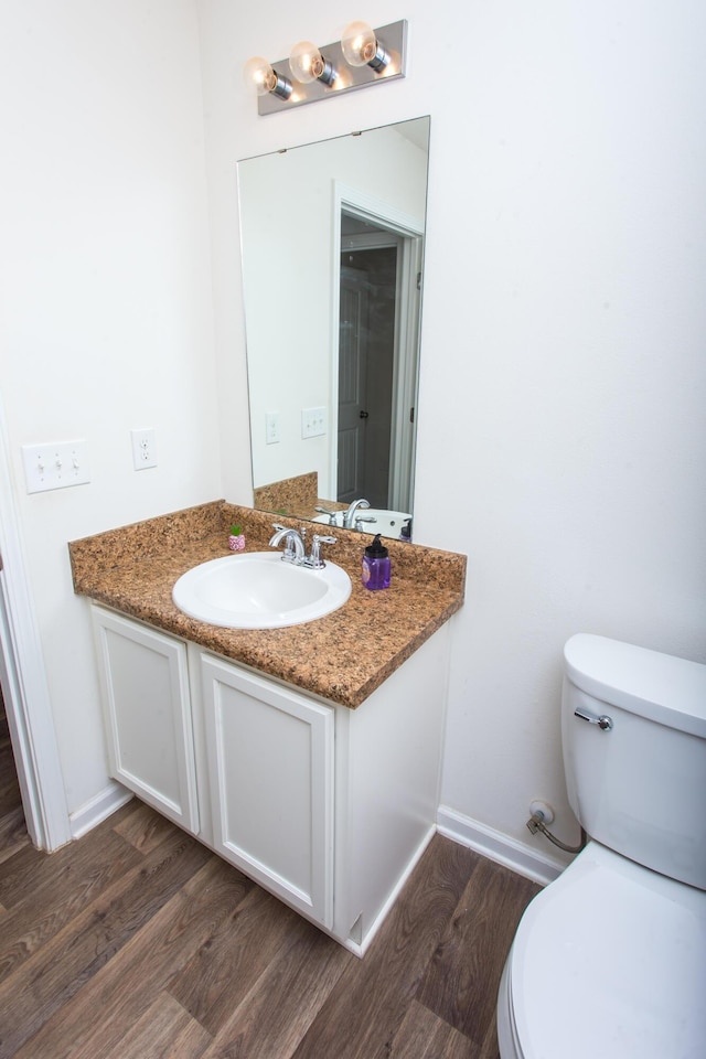 bathroom featuring toilet, wood finished floors, baseboards, and vanity
