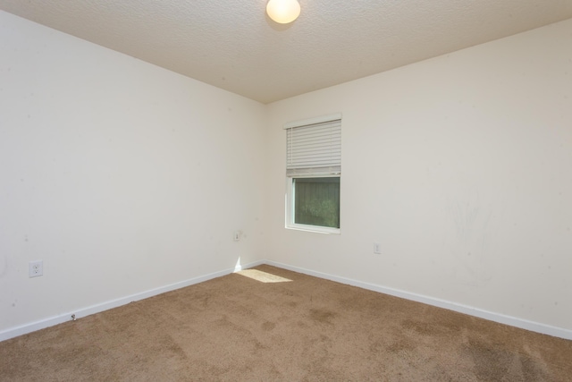 carpeted empty room with baseboards and a textured ceiling